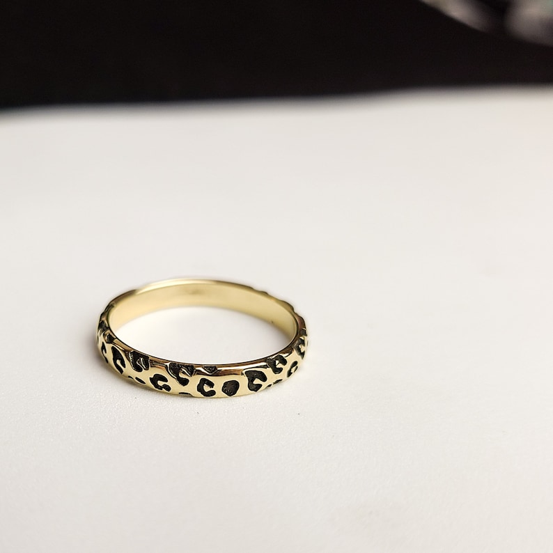 May include: A gold ring with a black leopard print design.