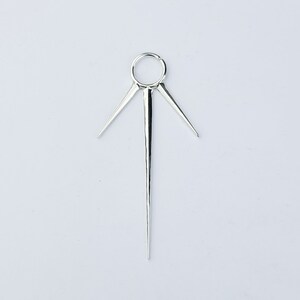 May include: Silver body jewelry with a circular hoop and three sharp points extending from the hoop.