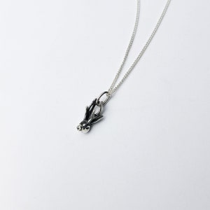 Puede incluir: Un collar de cadena de plata con un peque&ntilde;o colgante de plata en forma de asta de ciervo.