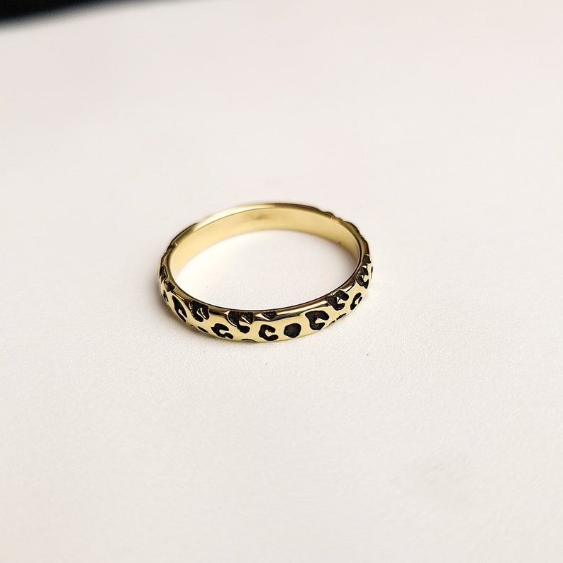 May include: A gold ring with a leopard print design.