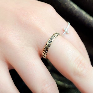 May include: A gold ring with a textured leopard print design. The ring is worn on a finger.