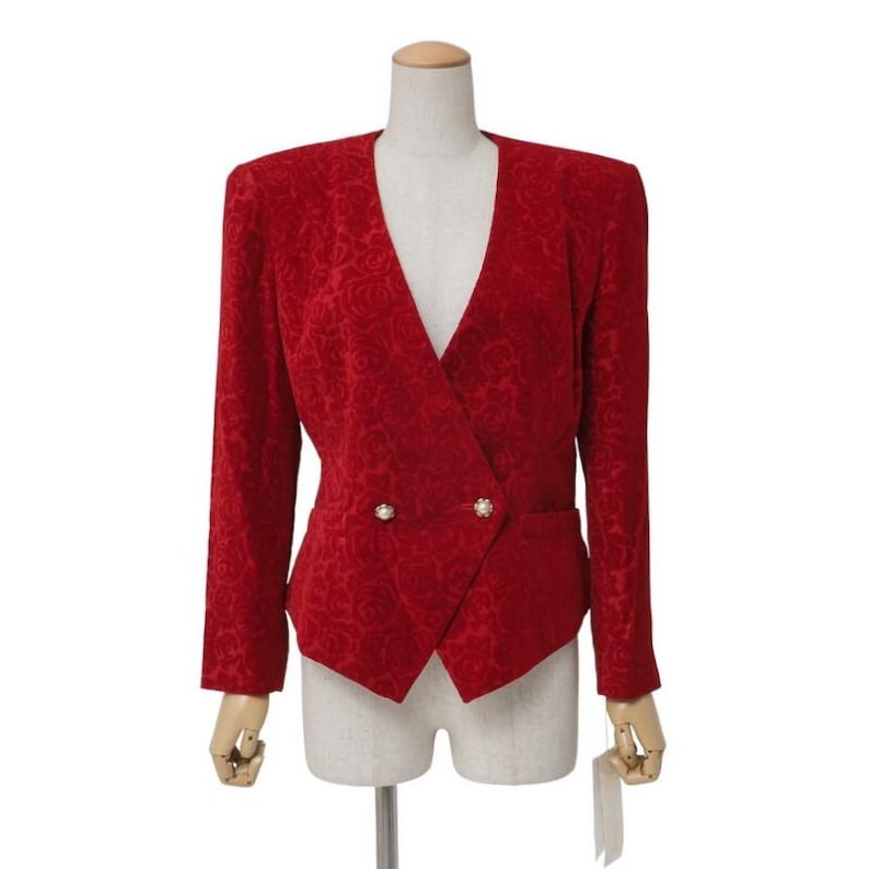 May include: A red blazer with a floral pattern, double-breasted with two gold-colored buttons. The jacket has a V-neck and long sleeves. The blazer is displayed on a mannequin.