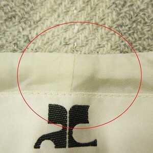 May include: Close-up of a cream-colored fabric with a black logo at the bottom. The fabric has a textured appearance and a stitched seam. The logo is a stylized design.