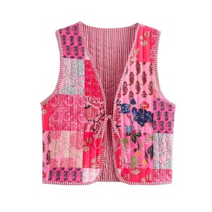 May include: A patchwork vest in shades of pink, featuring various floral and geometric patterns. The vest has a tie closure and a striped lining. The vest is sleeveless and has a quilted texture.