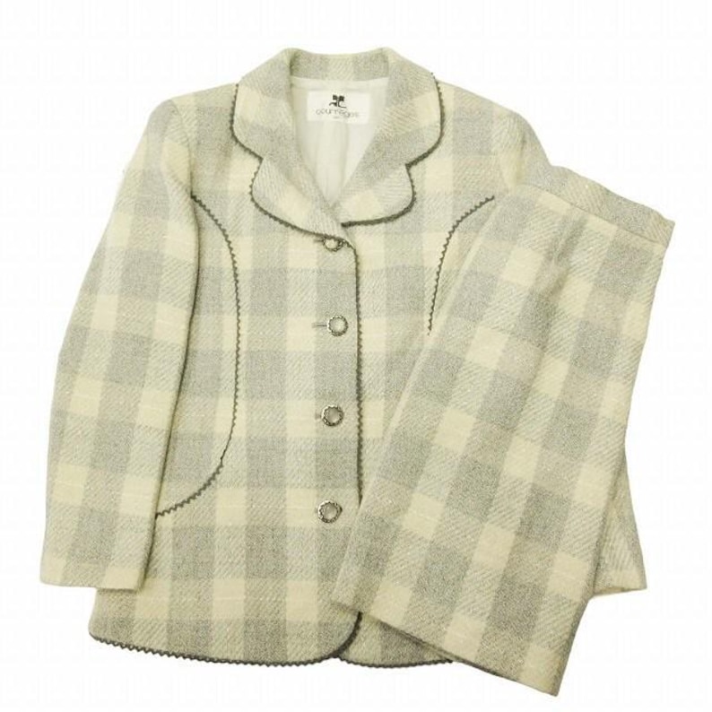 May include: A two-piece suit in a light gray and cream plaid pattern. The jacket has a notched collar, three silver buttons, and dark gray trim. The matching pants are straight-legged. The suit is made of a textured fabric.