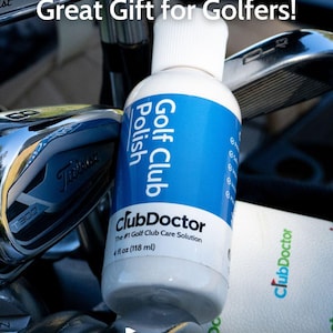 以下が含まれることがあります： 青いラベルが付いたClubDoctorゴルフ用クラブポリッシュの白いプラスチックボトル。Great Gift for Golfers!、ClubDoctor、The #1 Golf Club Care Solution、118mlという文字が記載されており、複数の金属製ゴルフクラブの間に置かれています。