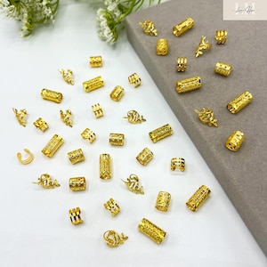 以下が含まれることがあります： 金色のジュエリーパーツのコレクション。ビーズ、チューブ、装飾的なアクセントが含まれています。これらのパーツは、形や大きさが異なり、表面はテクスチャード加工と滑らかさがあります。一部には複雑な葉や花の模様があり、その他はシンプルな円柱です。