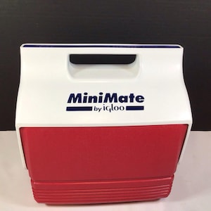 May include: A white and red plastic portable cooler featuring a top handle and the text MiniMate by igloo printed in dark blue on the front. The cooler has a rectangular shape with a textured red base and a smooth white lid section.