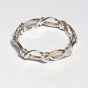 May include: A silver and gold intertwined ring with a unique knot design.