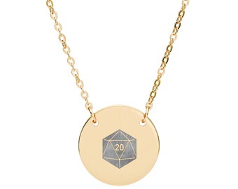 May include: A gold-coloured necklace with a circular pendant. The pendant displays a grey geometric die design with the number 20. The necklace is suspended from a fine gold chain, a simple and stylish accessory.