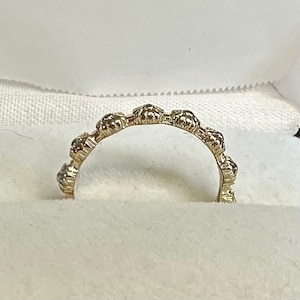 May include: A gold ring featuring a series of small, rounded, textured beads arranged in a continuous arc along the band. The metal has a warm, metallic yellow tone with a polished finish that catches the light across each individual bead element.