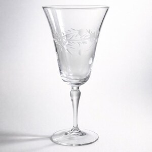 May include: Clear, stemmed wine glass with etched floral and dot design. The glass has a wide bowl and a slender stem, perfect for serving wine. The etched design adds a touch of elegance to the glassware.