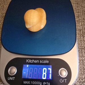 May include: A small, light orange-colored object sits on a blue kitchen scale. The digital display shows a weight of 188.87 grams. The scale is labeled "Kitchen scale" and has a maximum capacity of 10000g.