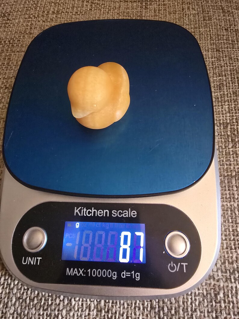 May include: A small, light orange-colored object sits on a blue kitchen scale. The digital display shows a weight of 188.87 grams. The scale is labeled "Kitchen scale" and has a maximum capacity of 10000g.