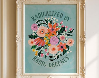 May include: Framed art print with a teal background, featuring a floral bouquet in pink, orange, and yellow. The text "RADICALIZED BY BASIC DECENCY" is displayed above and below the flowers. The frame is white and ornate.