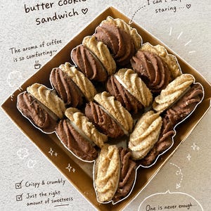 May include: A box of chocolate coffee butter cookie sandwiches. The cookies are a mix of light and dark brown, with a creamy filling. The image includes text that says "Crispy & crumbly", "Just the right amount of sweetness", and "Happiness in every bite..."