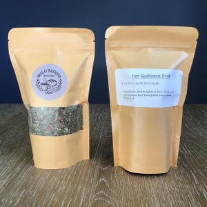 Puede incluir: Dos bolsas de t&eacute; color beige. Una muestra la mezcla de t&eacute; a trav&eacute;s de una ventana transparente. La otra tiene una etiqueta que dice "Her Radiance Brew". Los ingredientes incluyen hoja de frambuesa roja, hoja de alfalfa, hierba de lim&oacute;n, p&eacute;talo de rosa roja, melisa y hoja de ortiga.