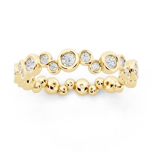 Könnte beinhalten: Ein goldener Ring mit einem einzigartigen Design aus abwechselnd gefassten Diamanten und kleineren Goldkugeln. Das Design des Rings erzeugt ein blasenartiges, strukturiertes Aussehen, wobei die Diamanten Glanz verleihen.