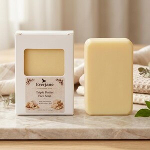 May include: A light yellow Triple Butter Face Soap bar next to its white box. The box has a window showing the soap and a label with the brand name and product details. The soap is 113g.