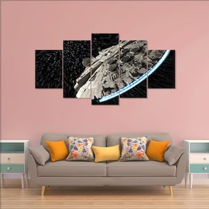 Puede incluir: Un conjunto de arte mural de lienzo de cinco paneles que presenta una representación detallada de una nave espacial en el espacio. La nave espacial es principalmente gris con detalles azules y blancos, sobre un fondo negro con rayas blancas. La obra de arte se exhibe sobre un sofá gris con cojines coloridos.