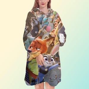 May include: A hooded sweatshirt featuring a colorful print of characters from the animated movie Zootopia. The design includes images of Nick Wilde, Judy Hopps, and other characters. The sweatshirt has long sleeves and a hood.