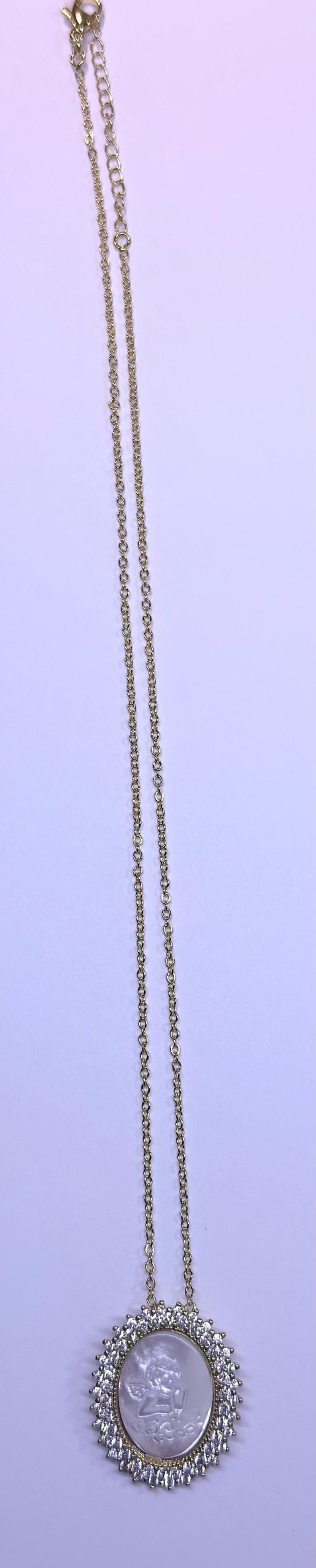 May include: Gold-toned necklace with a pendant featuring a central oval design with an angel figure, surrounded by clear crystals. The chain is delicate and hangs against a light background.