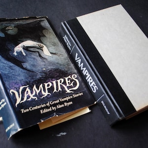 May include: Two book covers with the title "Vampires" on the spine and front. The front cover features a black and white illustration of a vampire bat carrying a person.