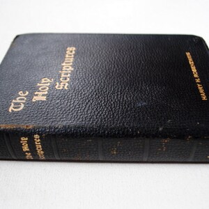May include: A black leather-bound book with gold lettering on the cover that reads "The Holy Scriptures". The spine of the book has the text "The Holy Scriptures" and "Harry H. Rosenbloom" in gold lettering.