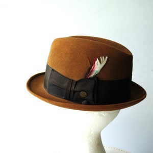 May include: A brown fedora hat with a black ribbon and a small feather accent.
