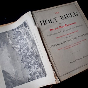May include: An open book with a black and white illustration on the left page and the title "The Holy Bible, Old and New Testaments, Translated Out of the Original Tongues" on the right page. The text "Special Explanatory Features" is also visible on the right page.