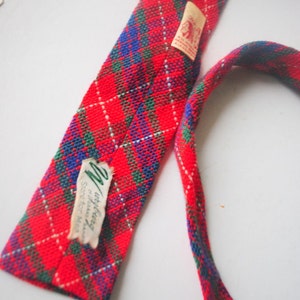 May include: Red, green, and blue plaid tie with a white label that says "Intrigue, Scotch for Men".