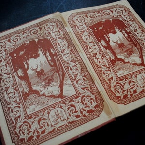 May include: A vintage book with a red and white patterned cover. The cover features a decorative border with a floral design. The book has a scene of a deer in a forest printed on the front cover.