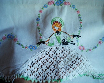 Könnte beinhalten: Weißer Baumwollstoff mit einer gehäkelten Kante und gestickten Blumen und einem Mädchen in einem grünen Kleid.