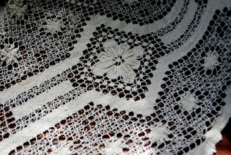 K&ouml;nnte beinhalten: Wei&szlig;e geh&auml;kelte Spitzentischdecke mit einem zarten Blumenmuster. Die Spitze ist filigran und detailliert, mit einer feinen Webart. Die Tischdecke ist perfekt, um jeder Tischdekoration einen Hauch von Eleganz zu verleihen.