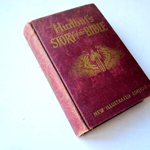 May include: A vintage burgundy book titled "Hurlbut's Story of the Bible" with gold lettering and illustration. The book is a New Illustrated Edition. The cover shows signs of wear, suggesting its age.