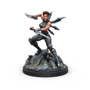 May include: A figurine of a female warrior in a dynamic pose, holding two silver daggers. She wears a gray bodysuit and stands on a rocky base. The figure has brown hair and is ready for battle. The base is a dark gray color.