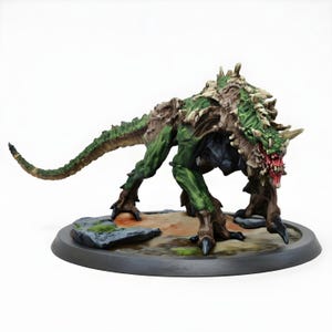 Può includere: Miniatura di mostro dipinta a mano, con una combinazione di colori verde e marrone. La creatura presenta denti e artigli affilati, posata su una base circolare con terreno roccioso. Perfetta per giochi da tavolo o esposizione.