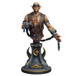 Puede incluir: Busto detallado de una figura calva con orejas puntiagudas, que lleva una venda en los ojos y un chaleco marrón. La figura está adornada con cadenas plateadas y un collar. El busto está montado sobre un pedestal gris oscuro con detalles dorados, con un diseño de media luna.