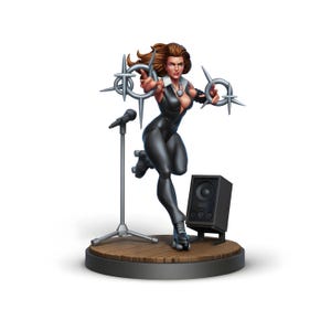 May include: A white ceramic mug with a black handle and the text "But First, Coffee" in a bold, black font. The mug is set against a blurred background, suggesting a cozy setting.