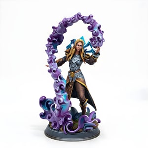 Puede incluir: Figura detallada de un personaje femenino con armadura de fantasía, sosteniendo un efecto de energía arremolinada púrpura y azul. La figura tiene cabello rubio y está posada sobre una base circular. La armadura es plateada y dorada, con detalles marrones.