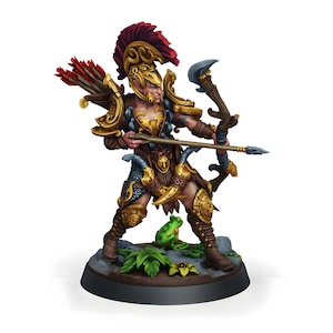 Puede incluir: Figura en miniatura de un arquero guerrero, vestido con una armadura dorada y marrón ornamentada, con un casco con plumas rojas. La figura posa con un arco y una flecha tensos, de pie sobre una base rocosa con una pequeña rana verde.