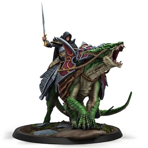 Puede incluir: Figura en miniatura de una figura encapuchada montada sobre un dragón verde, con una espada en alto. El dragón tiene la boca abierta, mostrando los dientes. El jinete lleva una armadura plateada y un escudo rojo y dorado.