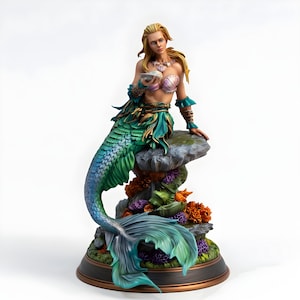 以下が含まれることがあります： ブロンドの髪の毛で貝殻を持っている、詳細な人魚の置物。人魚はピンクと紫の貝殻のトップス、緑とティールのスカート、青と緑の尾を着用しています。置物は、サンゴと海藻のある岩の上に座っています。
