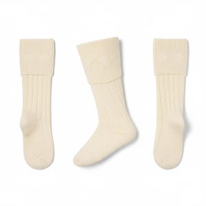 May include: Three ivory-colored socks are displayed against a white background. The socks have a ribbed design on the leg and a diamond pattern on the folded cuff. The socks are made of a soft, knitted material.