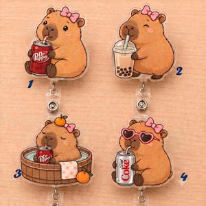 May include: Four acrylic badge reels featuring cartoon capybaras. One holds a Dr Pepper can, one drinks boba tea, one sits in a wooden tub with a Dr Pepper can and oranges, and one wears heart-shaped sunglasses while holding a Diet Coke can.