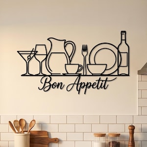 Op de afbeelding: Zwarte metalen wandkunst met silhouetten van keukengerei en drinkgerei, waaronder een wijnfles, glazen en een kan. De zin "Bon Appetit" is in cursief schrift eronder geschreven. Geschikt voor een keuken of eetkamer.