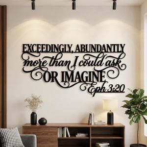 May include: A black wall-mounted sign featuring the text EXCEEDINGLY, ABUNDANTLY more than I could ask OR IMAGINE Eph 3:20 in a combination of bold block lettering and elegant cursive script, creating a decorative display for interior wall spaces.