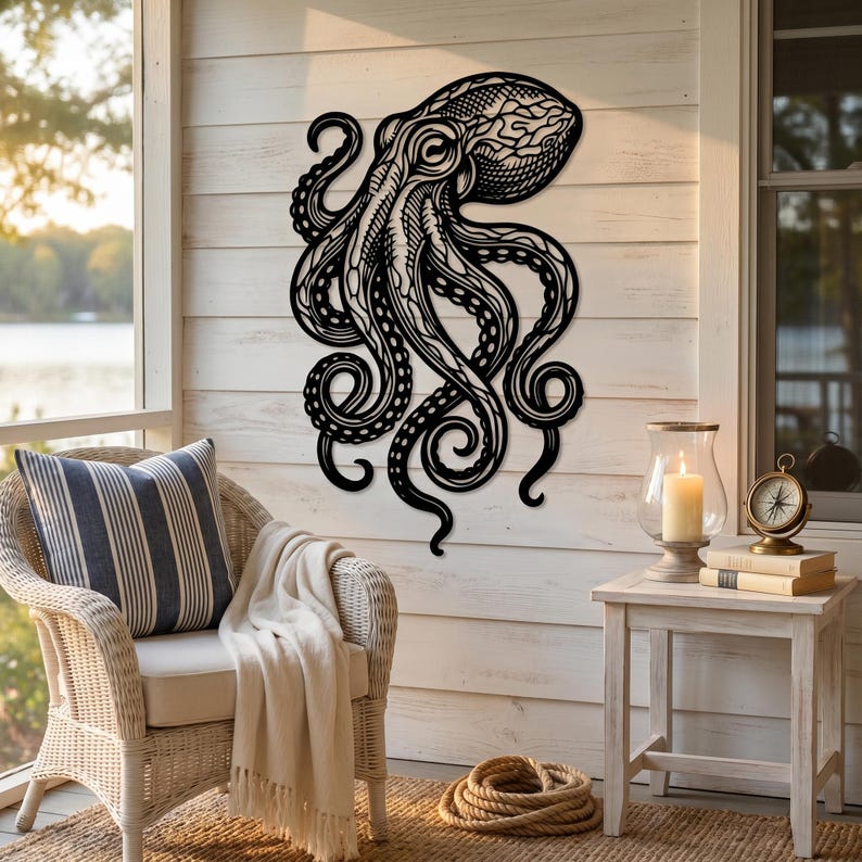 May include: Black metal octopus wall art with intricate cut-out details. The octopus has a detailed head and flowing tentacles. The artwork is mounted on a white wooden wall, creating a striking contrast. This nautical-themed decor adds a unique touch to any space.