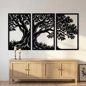 May include: A triptych of black metal tree wall art. Each panel features a detailed silhouette of a tree with branches, leaves, and roots. The art is set against a white background, creating a striking contrast. The panels are framed in black.