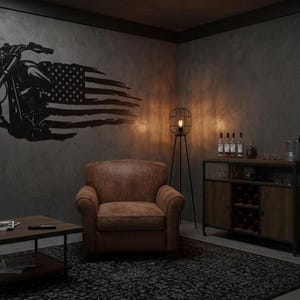 May include: A black metal motorcycle wall art piece with an American flag design. The artwork is mounted on a gray wall in a room with a leather armchair, a wooden cabinet, and framed motorcycle prints.